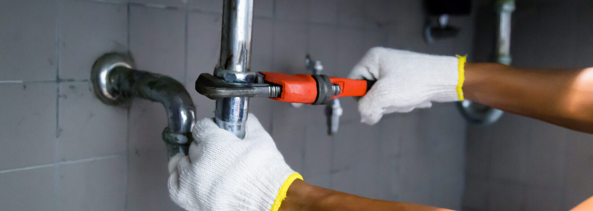 Plumber Fixing White Sink Pipe With Adjustable Wrench.